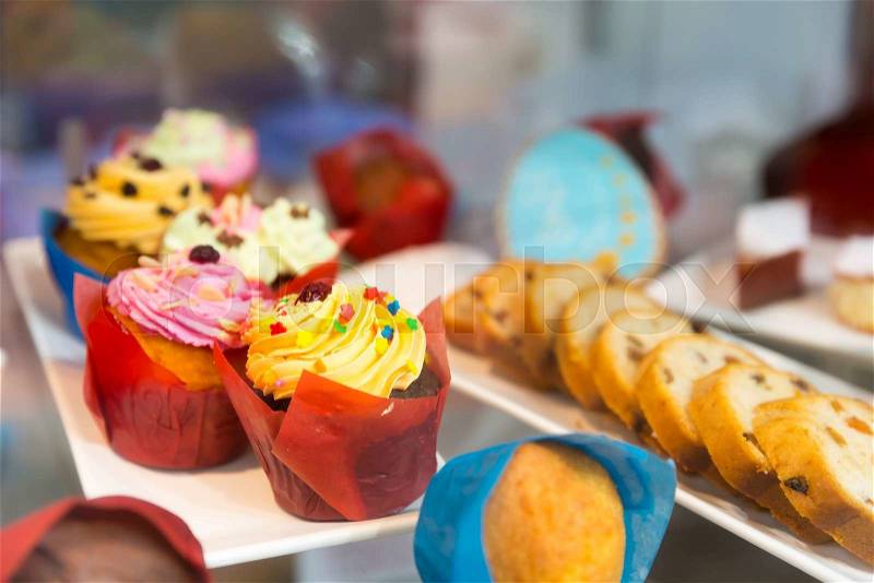 Sweet cakes in colored packing on the shelf in the shop, stock photo