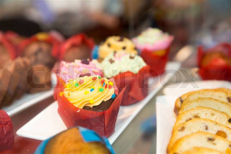 Sweet cakes in colored packing on the shelf in the shop, stock photo