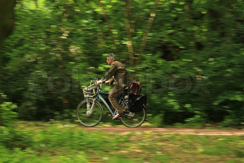 The teacher is in a hurry to school on the bike in the urban park in the city Groningen in spring, stock photo