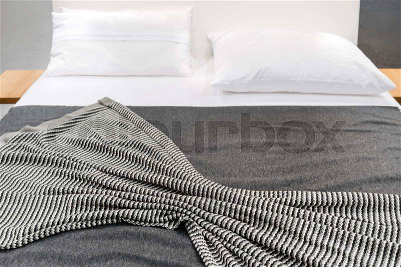 Bed with gray striped cover and white pillows, stock photo