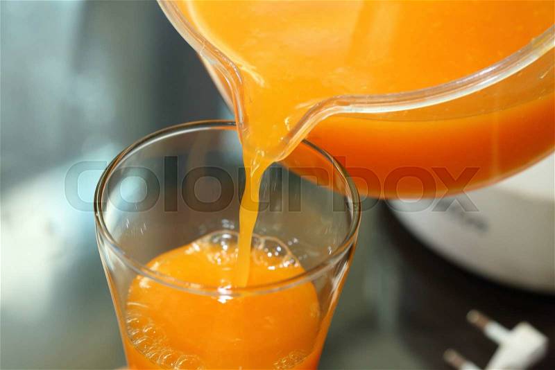 Fresh orange juice pouring from a jug into the glass, stock photo