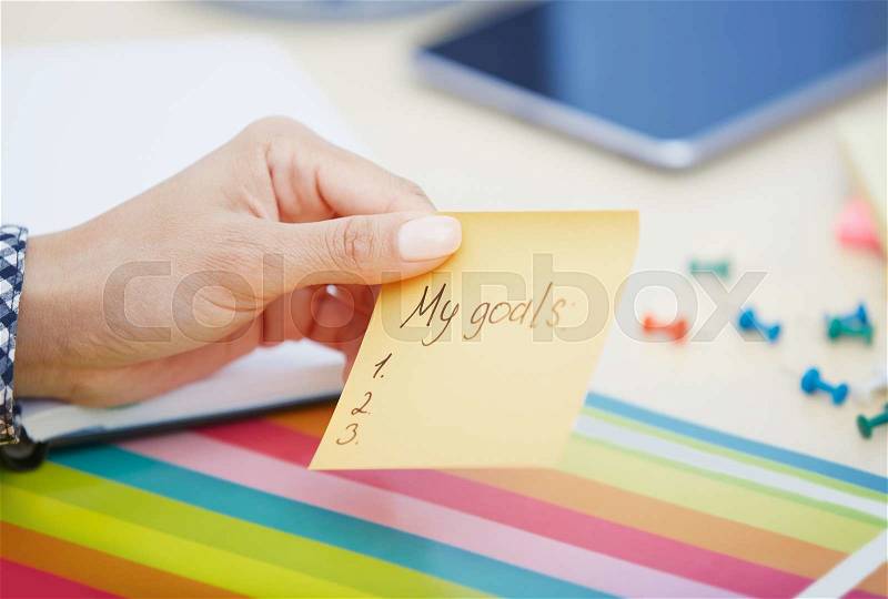 Human hand holding adhesive note with My goals text, stock photo