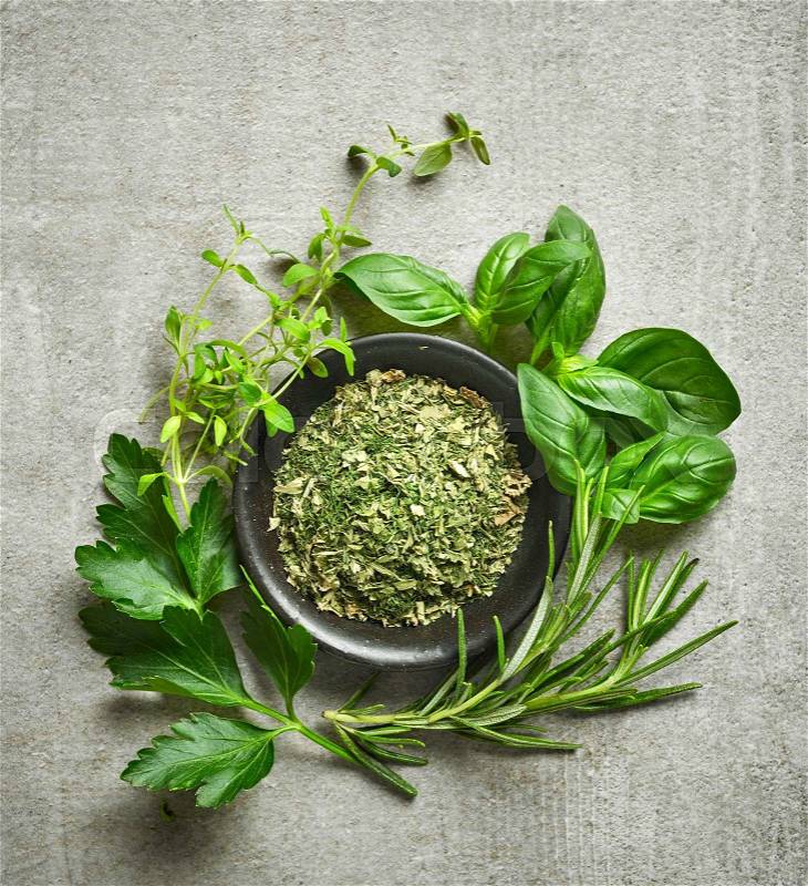 Bowl of dried herbs and fresh herbs on gray stone background, top view, stock photo
