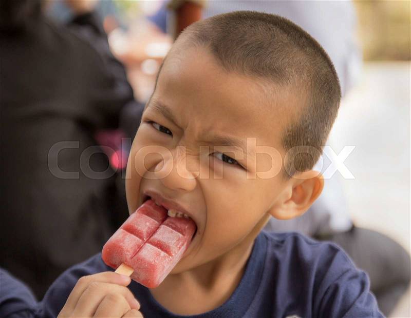 Asian boy eating ice cream bar with gusto, stock photo