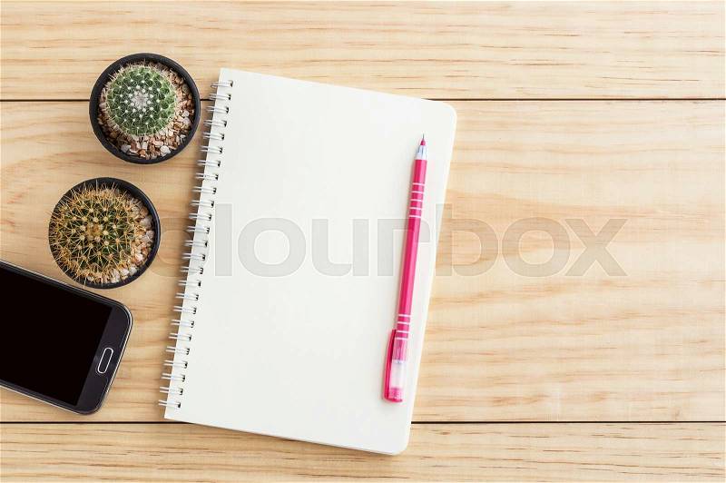 Vintage office desk table with notebooks,smart phone, pen and a cactus. Top view with copy space, stock photo