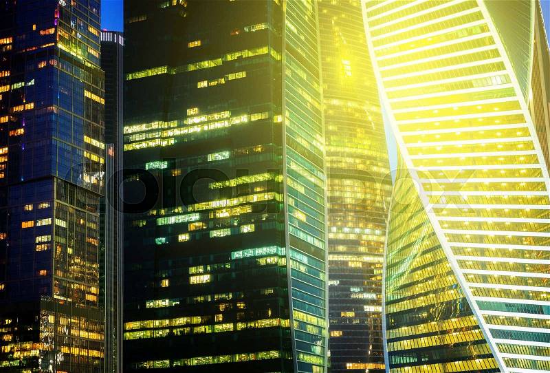 Illuminated windows of modern glass buildings background, toned, stock photo