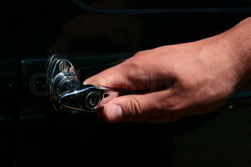 The man's hand opens a door of the ancient car, stock photo