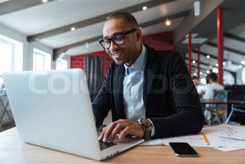 Young employee looking at computer monitor during working day in office, stock photo