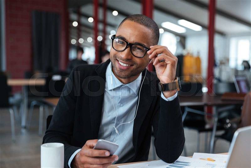 Businessman smiling and touching his glasses at the laptop, stock photo