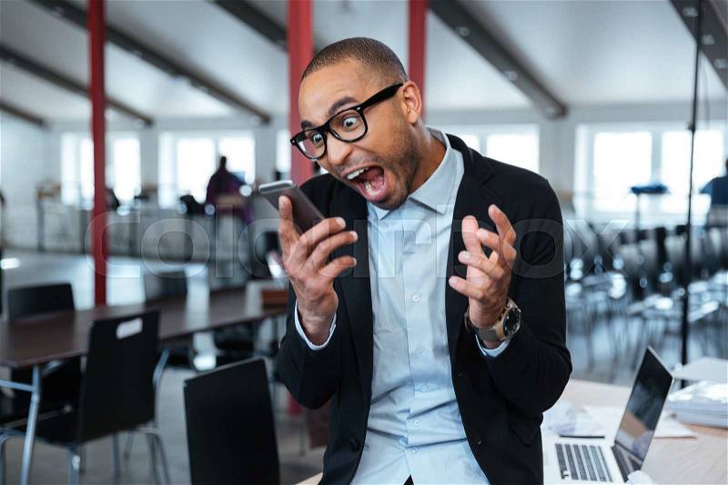 Furious mad bisnessman talking shouting on the phone in the office, stock photo