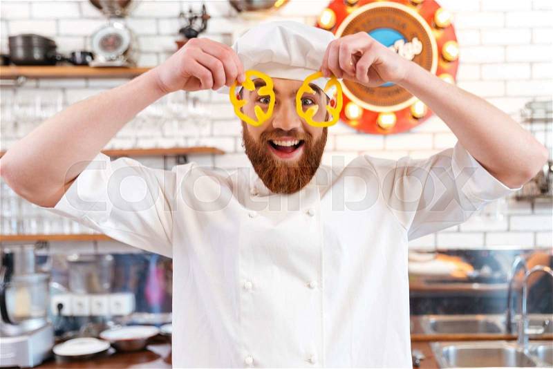 Funny chef cook looking through slices of yellow bell pepper, stock photo