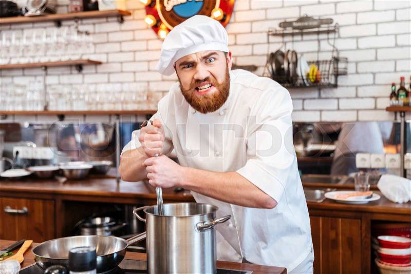 Funny bearded chef cook standing and cooking soup on the kitchen, stock photo