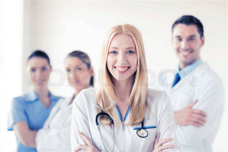 Attractive female doctor in front of medical group, stock photo