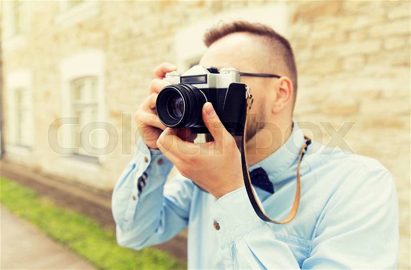 People, photography, technology, leisure and lifestyle - close up of young hipster man with retro vintage film camera on city street, stock photo