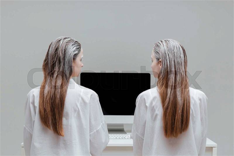 Two fashion mystic women looking at the blank monitor over gray background, stock photo