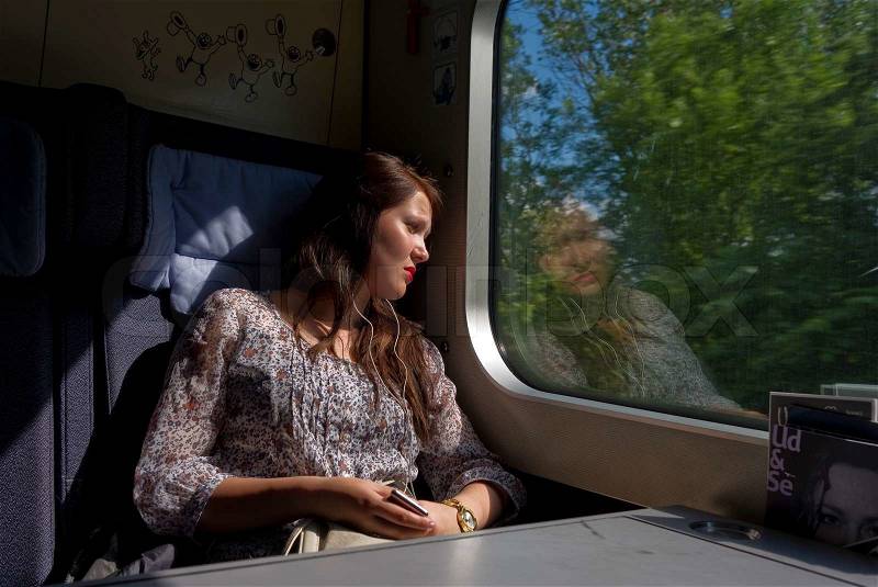 Young attractive girl in a blue mood listening to music in the train on her way home from a weekend by her boyfriend, stock photo
