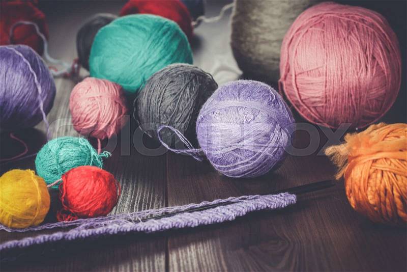 Knitting needles and balls of threads on wooden table, stock photo