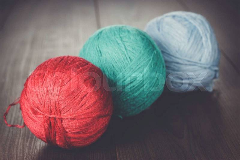Three knitting balls of threads on wooden table, stock photo