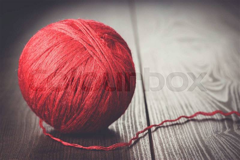 Red ball of threads on wooden table, stock photo