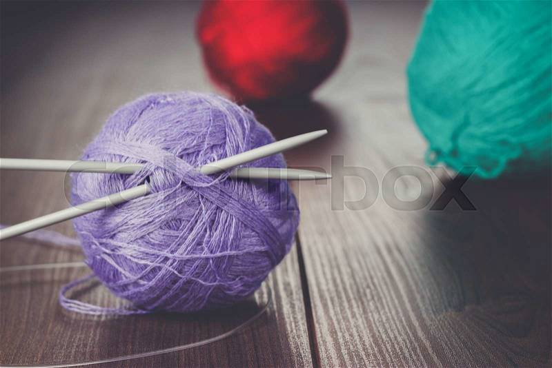 Knitting needles and balls of threads on the wooden table, stock photo