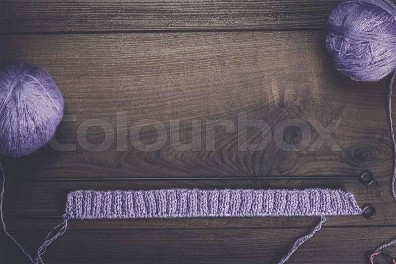 Knitting needles and balls of threads over wooden background, stock photo