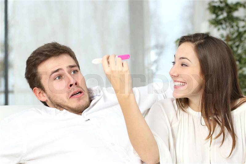 Excited woman getting pregnant to keep to her scared not ready partner at home interior, stock photo