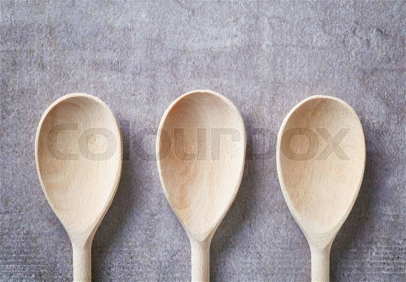 Three empty wooden spoons on stone table, top view, stock photo