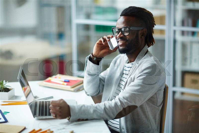 Casual businessman talking on the phone indoors, stock photo