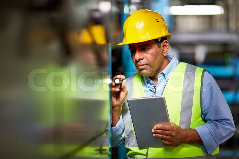 Mature engineer with small flash-light and touchpad, stock photo
