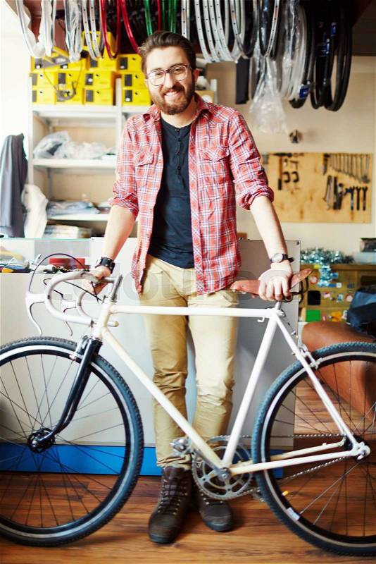 Portrait of young smiling man standing with bicycle, stock photo