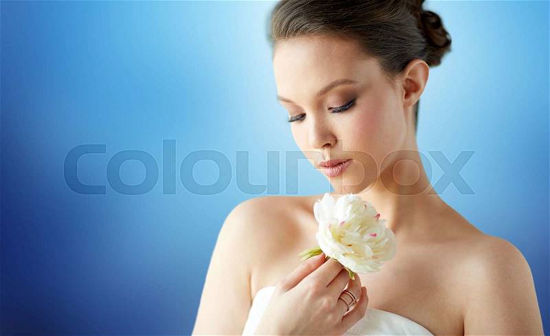 Beauty, jewelry, people and luxury concept - beautiful asian woman or bride in white dress with peony flowe and golden ring over blue background, stock photo