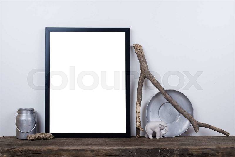 Scandinavian style empty photo poster frame mock up. Minimal home decor on rustic wooden board with white wall background, stock photo