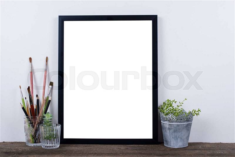Scandinavian style empty photo poster frame mock up. Minimal home decor on rustic wooden board with white wall background, stock photo