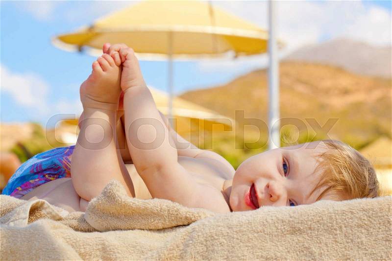 Smiling baby resting on the beach sunbed. Summer baby holidays, stock photo