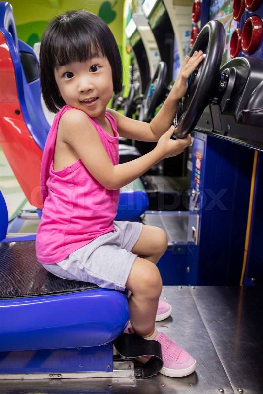 Asian Little Chinese Girl Playing Arcade Game Machine at a indoor Amusement Playground, stock photo