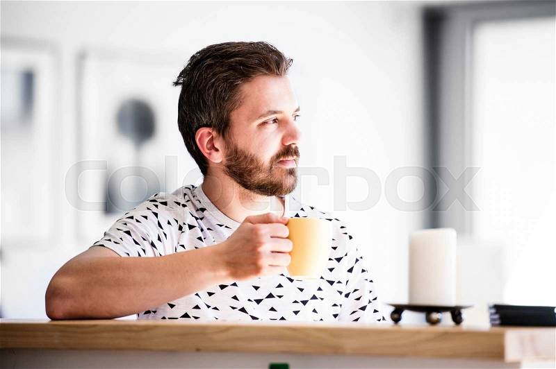 Handsome hipster businessman working from home, taking a break, drinking coffee, stock photo