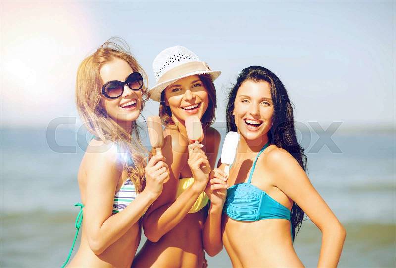 Summer holidays and vacation - girls in bikini with ice cream on the beach, stock photo