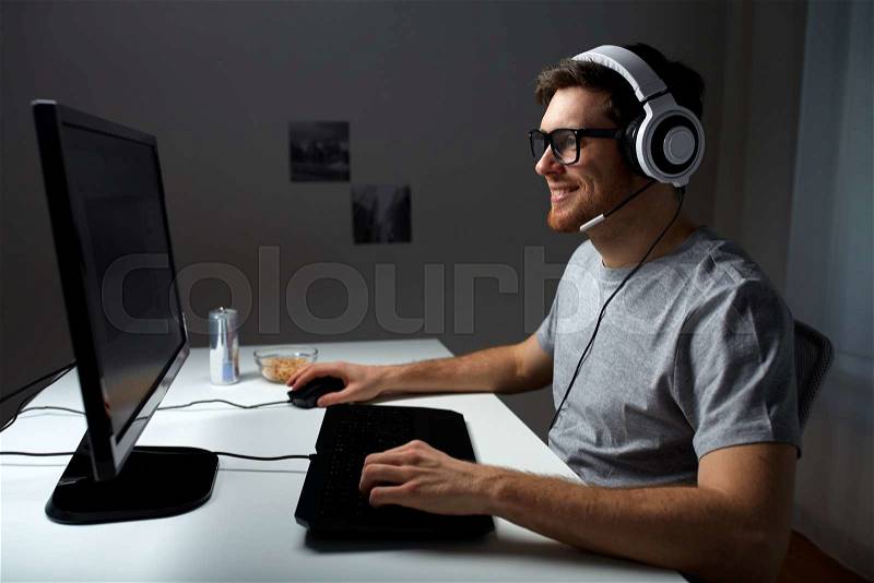 Technology, gaming, entertainment, let\'s play and people concept - happy young man in headset and glasses with pc computer playing game at home and streaming playthrough or walkthrough video, stock photo
