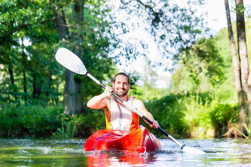 Man paddling with canoe on forest river, stock photo