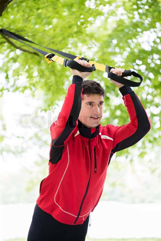 Man doing fitness sling training outdoors, stock photo