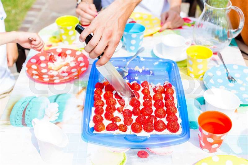 Family cutting fruit cake with knife, stock photo