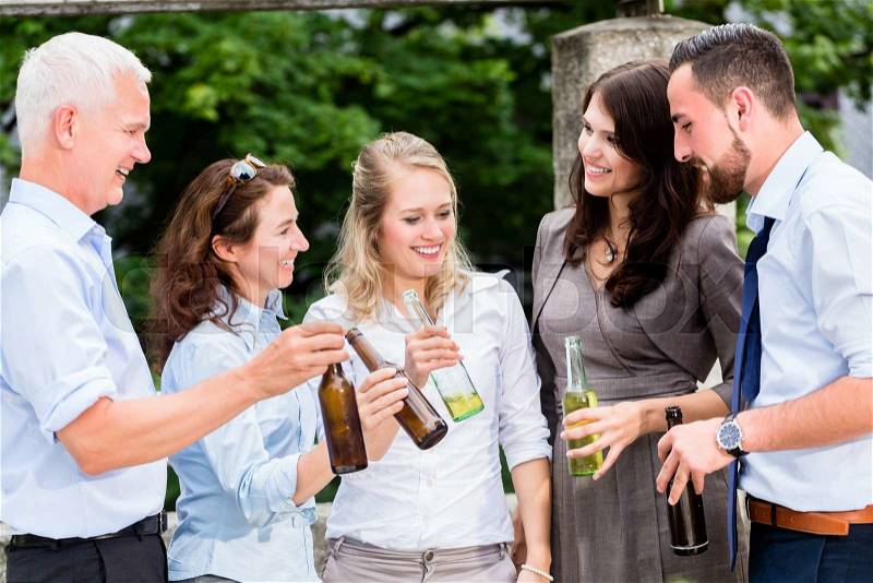 Office colleagues drinking beer after work on terrace celebrating, stock photo