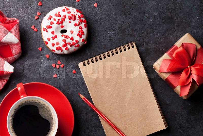 Donut, coffee and gift box on stone table. Top view with notepad for copy space, stock photo