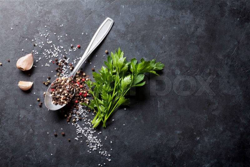 Garlic, black, white and red pepper and salt spices in spoon, parsley herb. Top view with copy space, stock photo