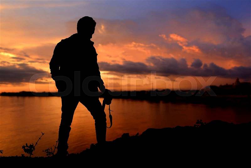 Silhouette of freedom photographer action with camera in sunset time dark and lowlight on the mountain view, stock photo