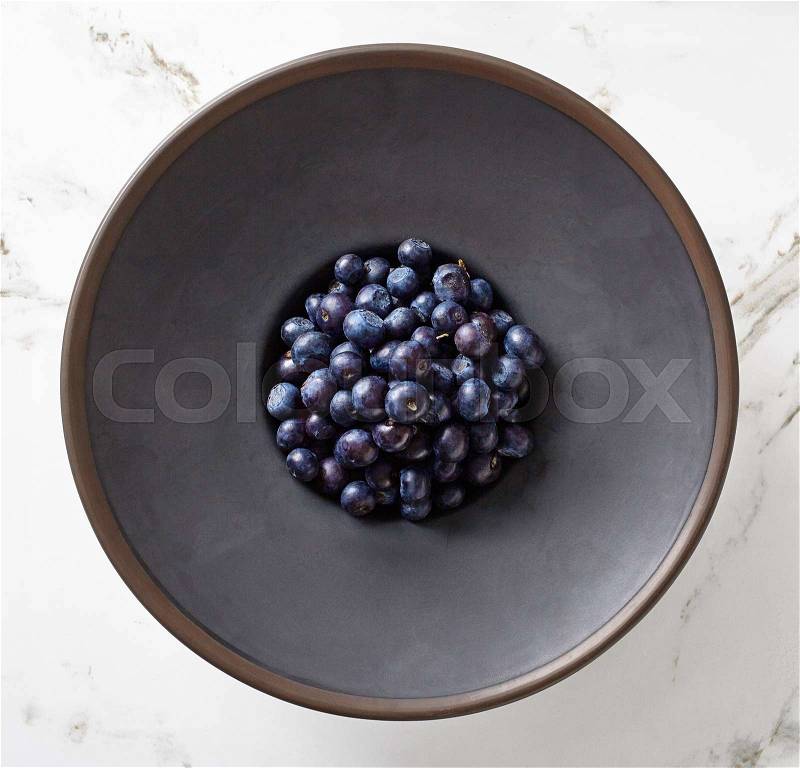 Bowl of ripe blueberries on marble table, top view, stock photo