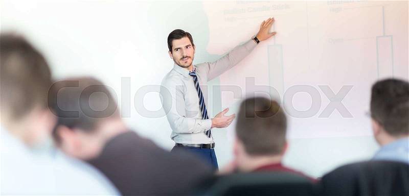 Business man making a presentation at office. Business executive delivering a presentation to his colleagues during meeting or in-house business training, explaining business plans to his employees, stock photo