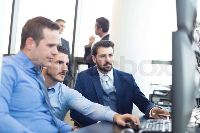 Business team looking at data on multiple computer screens in corporate office. Business people trading online. Business, entrepreneurship and team work concept, stock photo