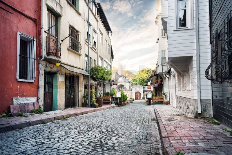 Narrow street lined with stone at sunset, stock photo