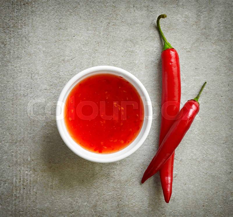 Bowl of sweet chili sauce on gray stone background, top view, stock photo